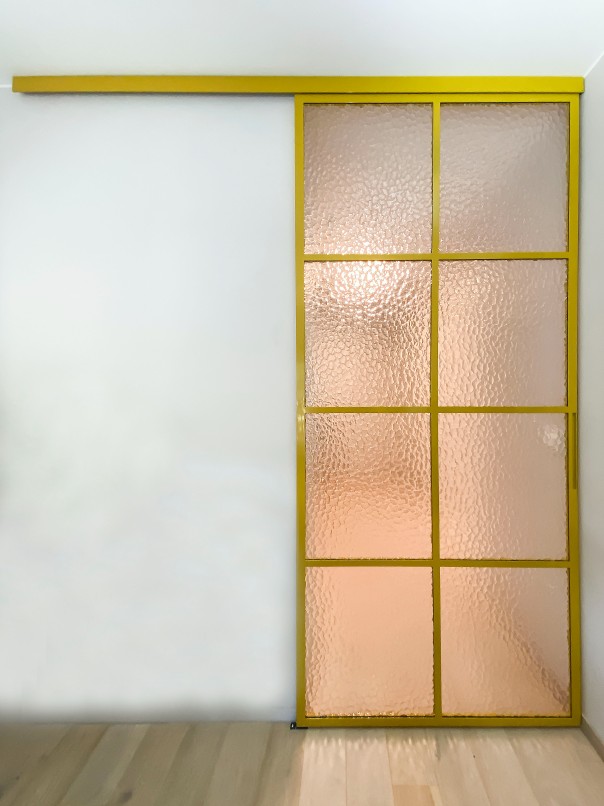 Enkel utenpåliggende skyvedør i gull farge og frostet glass